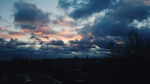 Cityscape against cloudy sky at sunset