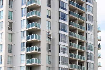 Rear view of man cleaning building windows