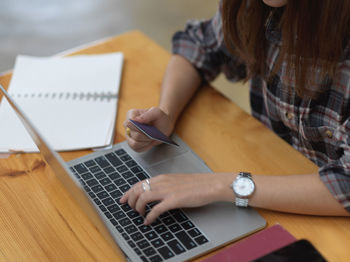 Midsection of woman paying bill sitting by table