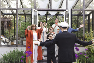 Happy family with arms outstretched welcoming young man at party