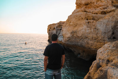 Rear view of man looking at sea against sky