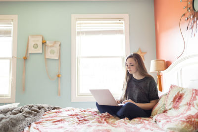 Woman using laptop computer on bed at home