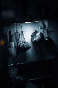 Close-up of kitchen utensils hanging at home in darkroom