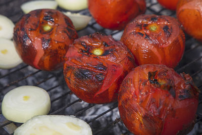 Close-up of grilled onions and tomatoes on barbecue grill