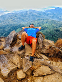 Rear view of man sitting on rock