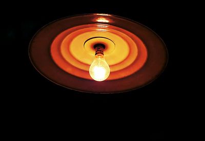 Low angle view of illuminated lamp against black background