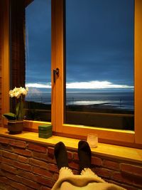 Low section of person relaxing on window at home