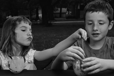 Cute siblings eating food while sitting outdoors