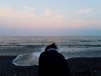 Low section of woman standing on beach against sky during sunset