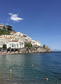Buildings by sea against blue sky