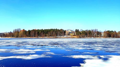 Scenic view of frozen lake against clear blue sky