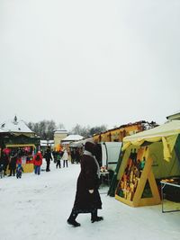 People on snow covered landscape against sky