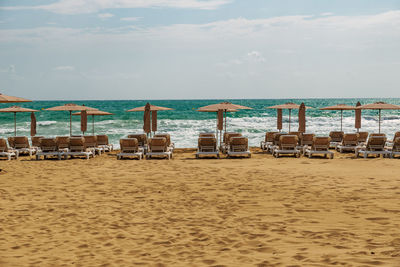 Deck chairs on beach against sky