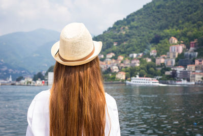 Rear view of woman in lake by mountains against sky