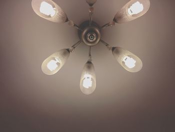 Low angle view of illuminated light bulb hanging from ceiling