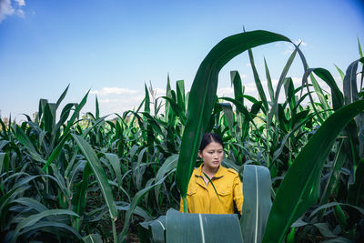 Woman looking away by plants growing in farm