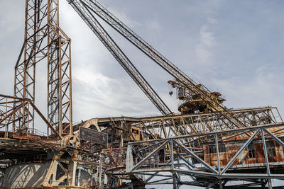 Low angle view of crane at construction site against sky