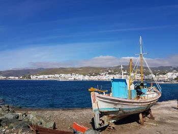 Sailboats moored on beach against blue sky