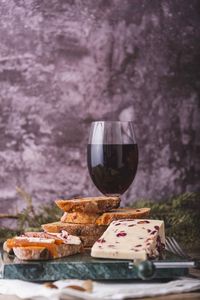 An assortment of various types of cheese with wine, and grapes, shot from above on a dark rustic