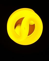 Close-up of yellow light bulb against black background