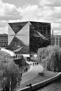 People by modern buildings against sky in city