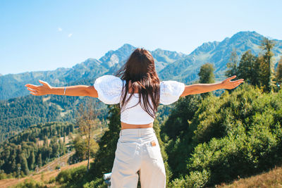 Rear view of person standing on mountain against sky