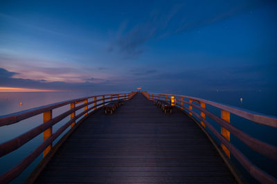 Footbridge over sea against sky at night
