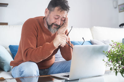 Young man using laptop while sitting on sofa at home