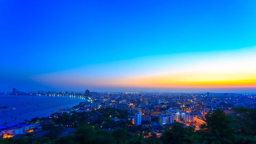 High angle view of illuminated buildings against blue sky