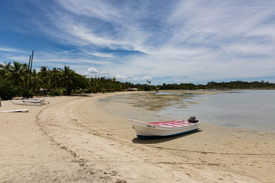 Boat moored on beach against sky