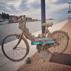 Close-up of bicycle by sea against sky