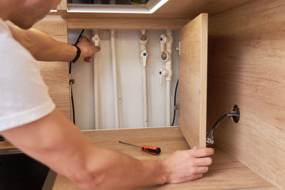 Man opens an assembly hatch and checks the water pipes