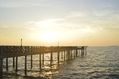 Pier on sea against sky during sunset