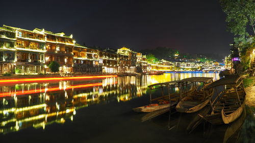 Illuminated bridge over river in city against sky at night