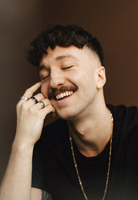 Smiling man day dreaming with eyes closed against brown background