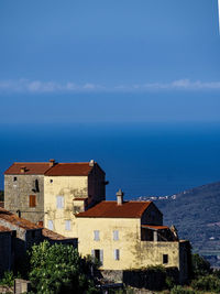 Houses by sea against sky