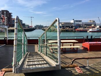 Pier by swimming pool in city against sky