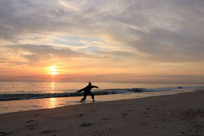 Silhouette person on beach against sky during sunset