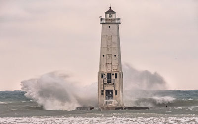 Lighthouse by sea against sky