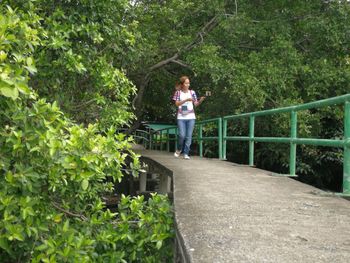 Woman standing by railing against trees