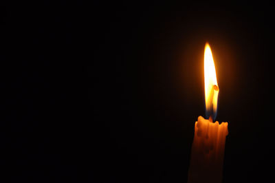 Close-up of lit candle against black background