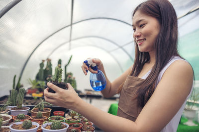 Woman looking at cactus in greenhouse garden center, asian young woman looking at small cactus