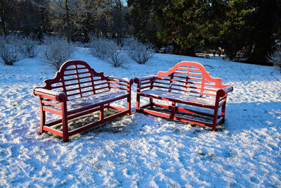 Empty bench in snow covered park during winter