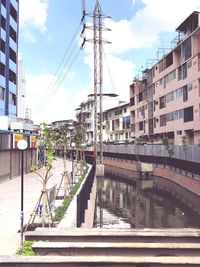 Bridge over canal by buildings in city against sky