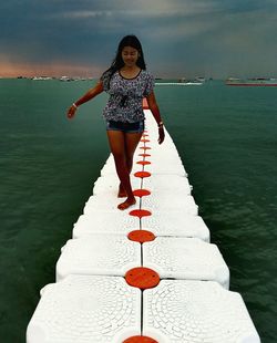 Full length of woman walking on jetty over sea