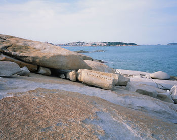Rocks on shore by sea against sky