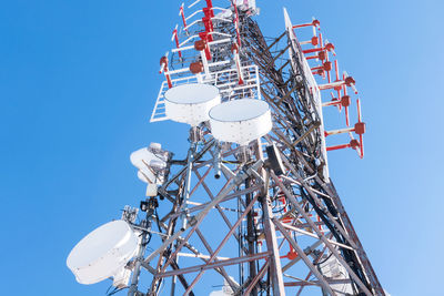 Low angle view of communications tower against clear blue sky