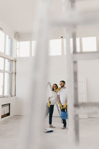 Happy smiling married couple engaged in renovation repair in the room of the house preparing to move