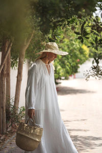 Woman wearing white dress walking in the garden barefoot