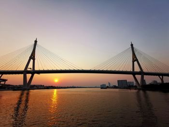 View of suspension bridge over river at sunset